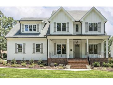 Inviting two-story home showcasing a classic facade, landscaped lawn, and brick-lined front porch at 201 S Ennis St, Fuquay Varina, NC 27526