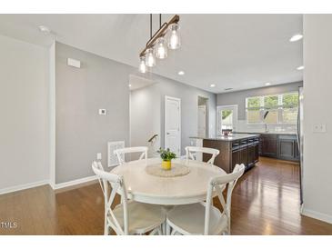 Cozy dining area features hardwood floors, a white round table with seating for four, and a modern pendant light at 2027 Hayes Ln, Holly Springs, NC 27540