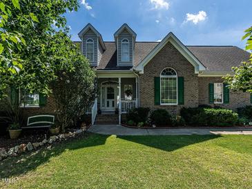 Charming brick home with lush green lawn, dormer windows, and manicured landscaping at 229 Hocutt Farm Dr, Clayton, NC 27527
