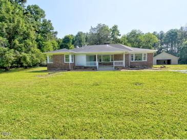 Charming brick ranch with a blue front door and a spacious front yard at 4414 Nc Hwy 87 N, Pittsboro, NC 27312