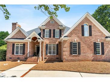 Charming brick home featuring a well-manicured lawn, black shutters, and an inviting covered front porch at 619 Baybush Dr, Raleigh, NC 27615