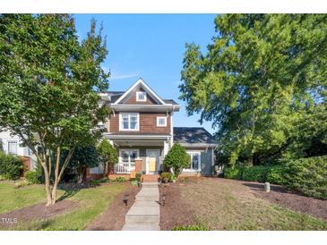 Charming two-story home with a welcoming front porch, mature trees, and well-manicured landscaping at 1009 Porchside Dr, Apex, NC 27502