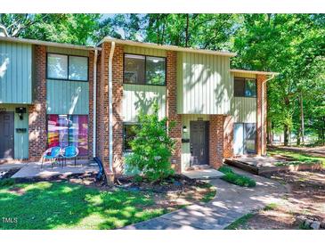 Inviting two-story brick townhome with mature trees, front porch, and well-manicured lawn at 1221 Teakwood Pl, Raleigh, NC 27606