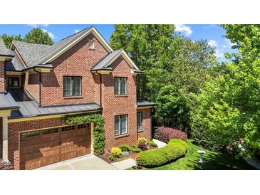 Charming brick home with lush landscaping, wooden garage door, and manicured lawn at 145 Cofield Cir, Durham, NC 27707