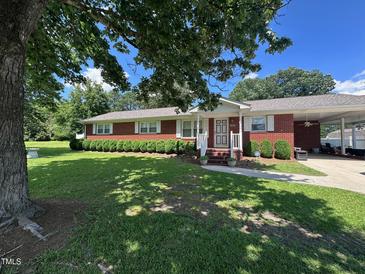 Charming brick home featuring a well-maintained front yard, carport, and inviting front porch at 1828 Fletchers Chapel Rd, Durham, NC 27703
