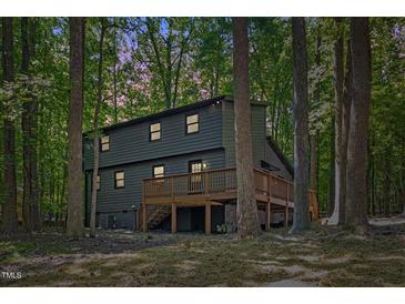 Rear exterior showing a large wooden deck perfect for outdoor entertaining surrounded by tall trees at 3218 Seven Springs Rd, Hillsborough, NC 27278