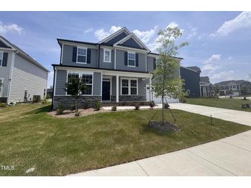 Charming two-story home with gray siding, stone accents, lush green lawn, and inviting covered front porch at 3509 Bailey Lake Dr, Fuquay Varina, NC 27526
