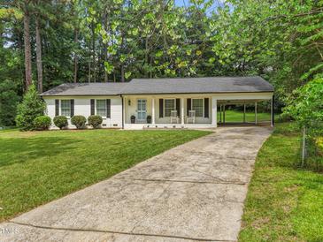 Charming brick home with a well-manicured lawn, rocking chair front porch, and covered parking at 404 Troy Pl, Raleigh, NC 27609