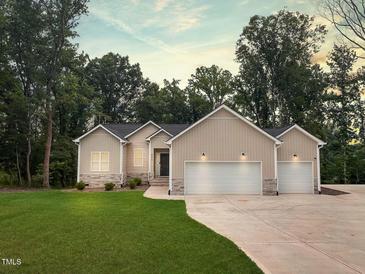 Charming home with a two-car garage, manicured lawn and natural surroundings at 620 Rollins Mill Rd, Holly Springs, NC 27540