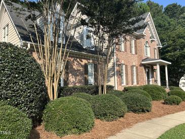 A charming brick two-story home with detailed landscaping and a welcoming front porch at 7801 Kingsbrook Ct, Wake Forest, NC 27587