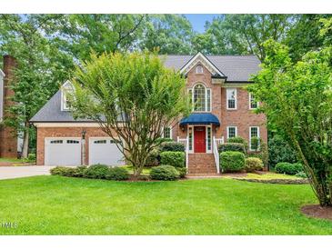 Charming brick home with manicured lawn, mature trees, and a welcoming red front door at 1030 W Sterlington Pl, Apex, NC 27502