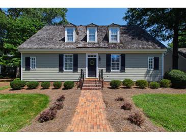 Charming single-story home with a brick walkway, manicured landscaping, and dormer windows at 107 Quarter Path, Cary, NC 27518