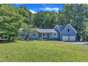 Charming blue home with a two-car garage and mature trees on a well-manicured lawn at 11100 Honeycutt Rd, Raleigh, NC 27614