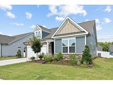 Beautifully landscaped home featuring stone accents, blue siding, and a well-manicured lawn at 125 Alumroot Rd, Holly Springs, NC 27540