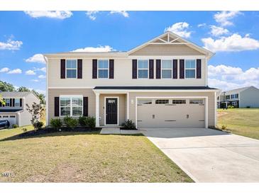Charming two-story home features beige siding, a two-car garage, and a well-maintained front yard at 16 Powder Ct, Angier, NC 27501