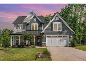 Charming two-story home featuring gray shingles, a manicured lawn, and a covered front porch at 220 W Amber Oak Dr, Selma, NC 27576