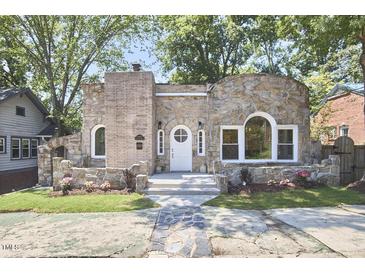 Charming stone home featuring unique architectural details, a well-manicured lawn, and mature trees at 2203 University Dr, Durham, NC 27707