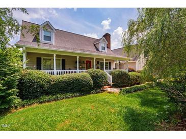 Inviting home featuring a charming front porch, manicured lawn, and beautifully landscaped shrubbery at 3619 Nc-57, Hillsborough, NC 27278