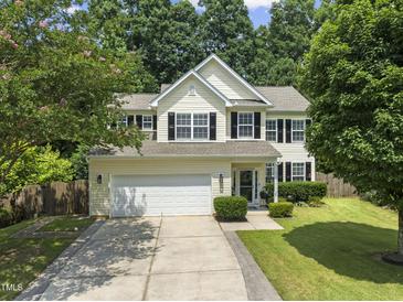 Charming two-story home with a well-manicured lawn, attached two-car garage, and mature trees in a lovely neighborhood at 404 Blooming Meadows Rd, Holly Springs, NC 27540