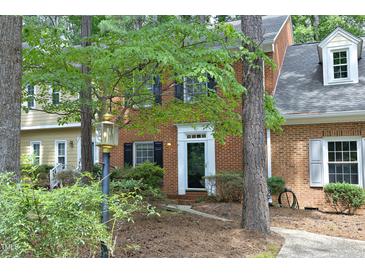 Charming brick townhome with manicured landscaping and inviting front entrance with black door and white trim at 747 Weathergreen Dr, Raleigh, NC 27615