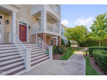 Inviting townhome exterior featuring a charming entrance with a red door, stairs, and a beautiful landscaped walkway at 10330 Sablewood Dr # 104, Raleigh, NC 27617