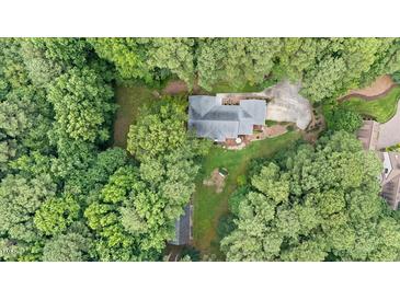 An aerial view of a home nestled among trees with a backyard deck and long driveway at 106 Autumn Cir, Cary, NC 27518