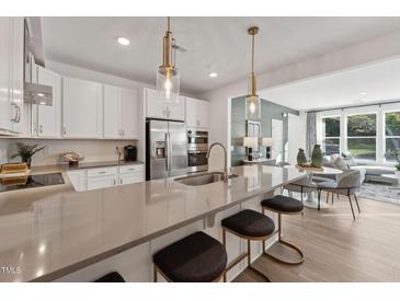Modern kitchen featuring a large island, stainless steel appliances, and stylish pendant lighting at 1232 S Person St # 101, Raleigh, NC 27601