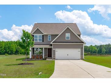 Inviting two-story home featuring a two-car garage, well-manicured lawn, and a charming covered front porch at 124 Lahinch Dr, Fuquay Varina, NC 27526