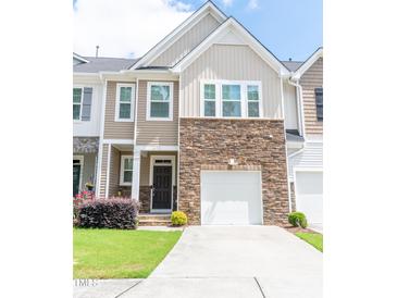 Charming townhome featuring a stone facade, attached garage, and a well-manicured lawn at 1402 Southpoint Trl, Durham, NC 27713