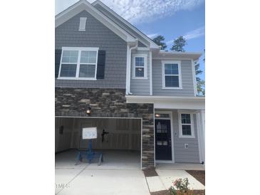 New construction home features a gray facade with stone accents and an attached two-car garage at 1524 Chirping Bird Ct, Cary, NC 27519