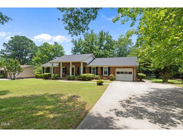 Charming brick home featuring a manicured lawn, mature trees, and a welcoming front porch at 1601 Redmond Dr, Durham, NC 27712