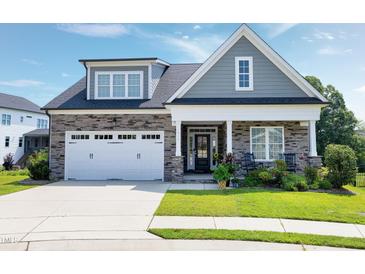 Charming home featuring a stone facade, white garage door and manicured front lawn at 1918 Morning Fog Dr, Fuquay Varina, NC 27526