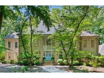 Stunning brick home with mature trees and a charming blue double-door entrance with wreath adornments at 2602 Vintage Hill Ct, Durham, NC 27712