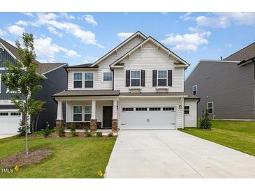 Charming two-story home with stone accents, a well-manicured lawn, and a two-car garage at 27 Silver Moon Ln, Clayton, NC 27527