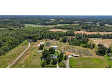 Expansive aerial view of a lush farm featuring fields, ponds, farm buildings, and a charming residence at 2856 Gwyn Rd, Elon, NC 27244