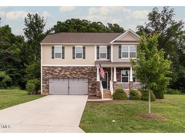 Two-story home with stone and siding, attached two-car garage, green lawn, and neatly trimmed shrubs at 3292 Longpine Rd, Burlington, NC 27215