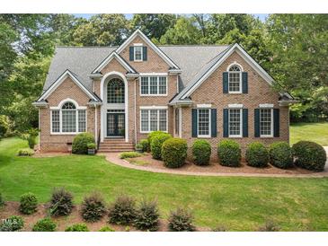 Traditional brick home featuring a manicured lawn, lush landscaping and eye-catching architectural details at 402 Bridewell Ct, Cary, NC 27518
