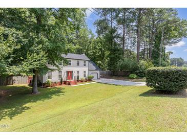 Charming two-story home with a red door and a spacious front yard with mature trees providing shade at 404 Sw Maynard Rd, Cary, NC 27511