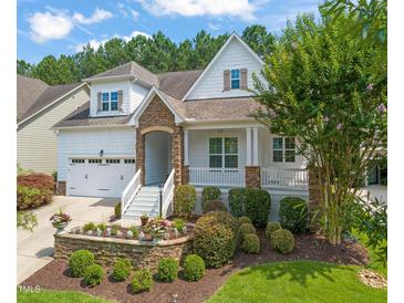 Charming two-story home featuring a welcoming front porch, well-manicured landscaping, and an attached two-car garage at 521 Morning Oaks Dr, Holly Springs, NC 27540