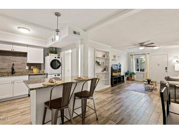 Open-concept living room with modern kitchen, sleek island seating, and an airy, inviting atmosphere at 7002 Longstreet Dr # C, Raleigh, NC 27615