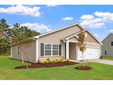 Charming home featuring stone accents, shutters, a two-car garage, and manicured lawn at 107 Flue Ct, Oxford, NC 27565