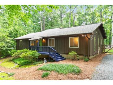 Charming exterior view of home with lush landscaping, wood siding, and a blue painted porch and trim at 1403 Meadow Ln, Chapel Hill, NC 27516