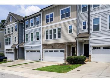Charming townhome exterior featuring a two-car garage, brick accents, and manicured lawn at 1434 Salem Dr, Apex, NC 27502