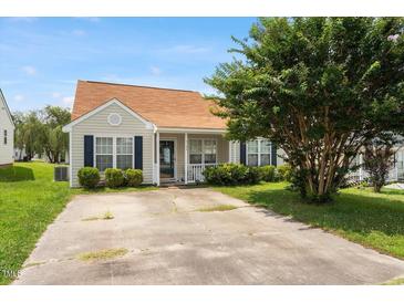 Charming home featuring manicured lawn, mature tree, and inviting front porch, perfect for relaxing outdoors at 5104 Parkerwood Dr, Knightdale, NC 27545