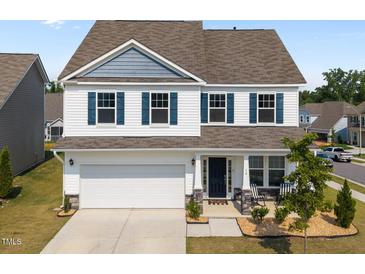Charming two-story home featuring white siding, blue shutters, a two-car garage, and a welcoming front porch at 14 Shady Oaks Rd, Angier, NC 27501