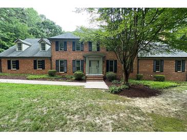 Inviting brick home with mature trees, manicured shrubs, and pathway leading to the front door at 14236 Wyndfield Cir, Raleigh, NC 27615