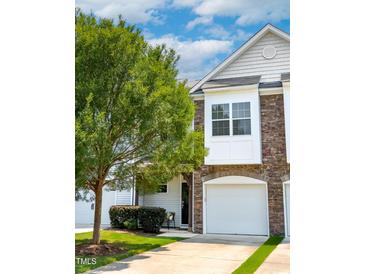 Inviting townhome showcases stone accents, a one car garage, and a well-manicured front yard at 16 Daly Ct, Durham, NC 27705