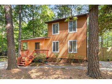 Two-story home surrounded by trees, featuring a front porch and ample natural light from numerous windows at 18 Frances St, Chapel Hill, NC 27517