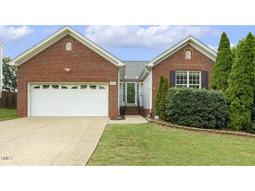 Charming brick home featuring an attached garage, well-maintained lawn, and manicured landscaping at 2012 Summer Shire Way, Raleigh, NC 27604