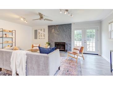 Bright living room featuring a stone fireplace, ceiling fan, stylish furniture, and access to outdoor space at 2014 Athens Ave, Durham, NC 27707